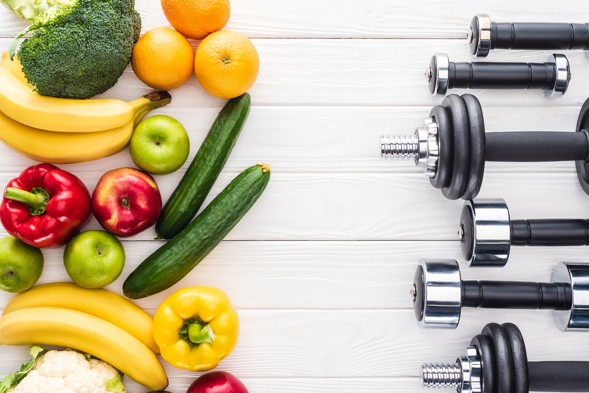 top view of fresh fruits with vegetables and various dumbbells on wooden surface
